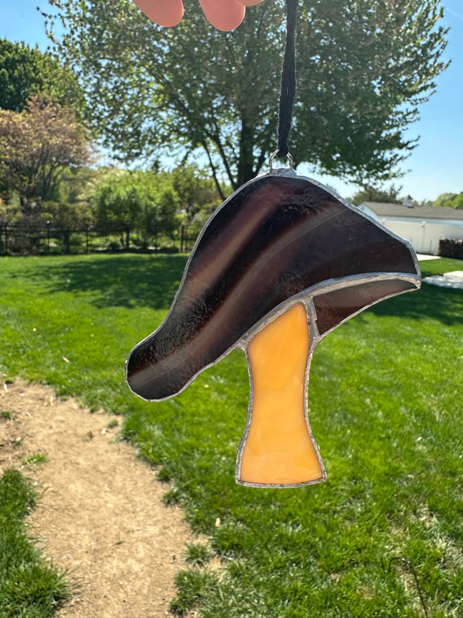 Single purple and amber stained glass mushroom suncatcher outdoors
